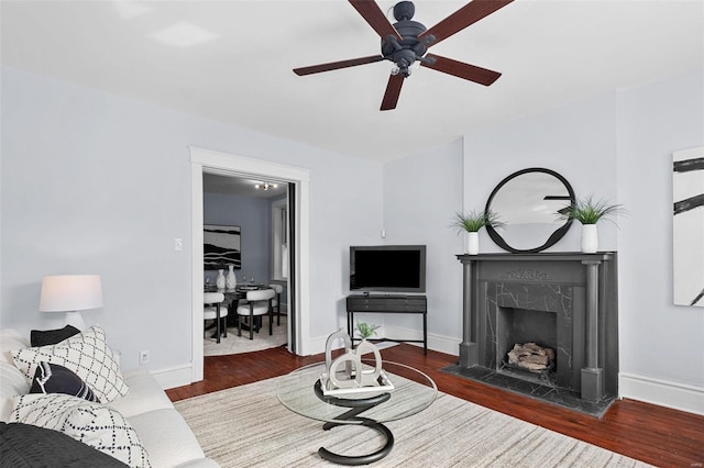 living area with baseboards, a high end fireplace, and dark wood-style floors