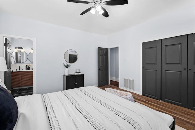 bedroom with a closet, ensuite bathroom, visible vents, dark wood-type flooring, and ceiling fan