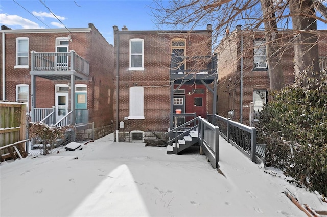 snow covered rear of property with brick siding