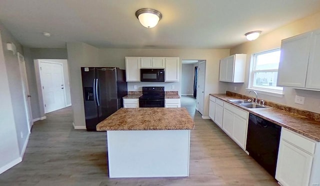 kitchen with black appliances, a kitchen island, white cabinetry, and a sink