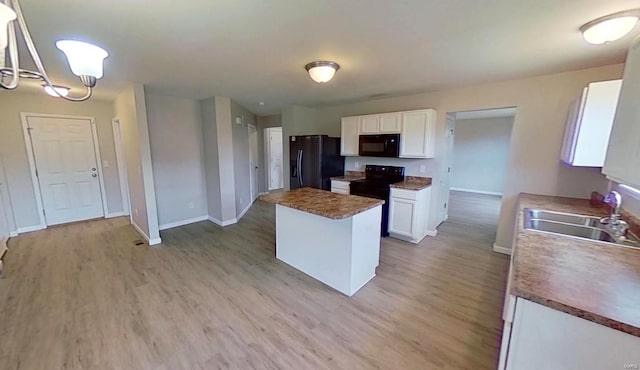 kitchen featuring white cabinets, light wood-style flooring, a center island, black appliances, and a sink