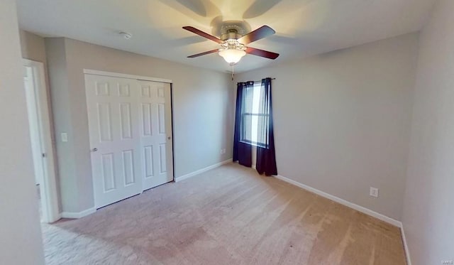 unfurnished bedroom with a ceiling fan, a closet, light colored carpet, and baseboards