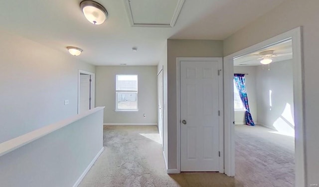 hallway featuring baseboards and light colored carpet