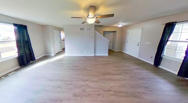 unfurnished living room with a ceiling fan, baseboards, visible vents, and wood finished floors