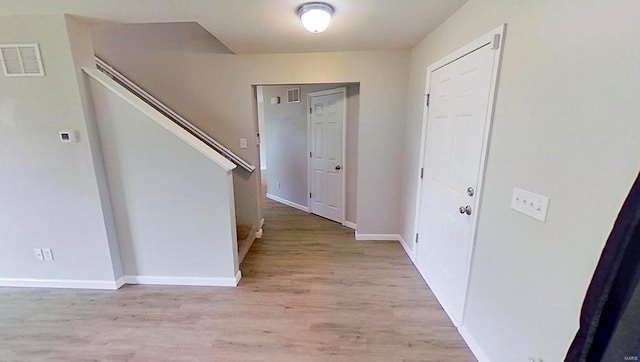 interior space featuring light wood finished floors, stairway, visible vents, and baseboards