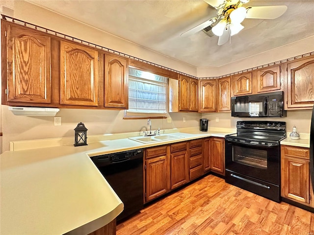 kitchen with brown cabinets, light countertops, a sink, and black appliances