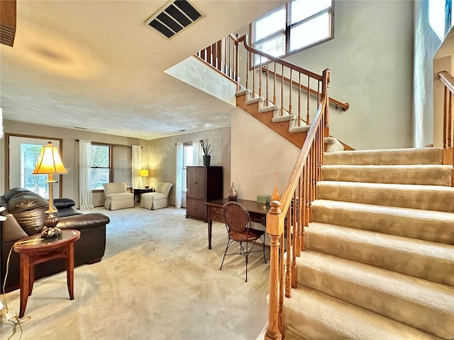 living area featuring stairway, carpet, and visible vents