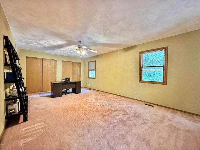 unfurnished office with light carpet, baseboards, visible vents, and a ceiling fan