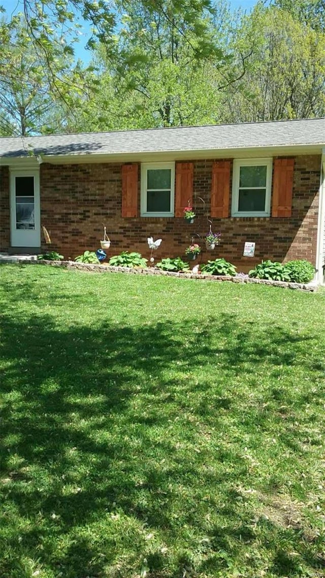 ranch-style home featuring brick siding, a front lawn, and a shingled roof