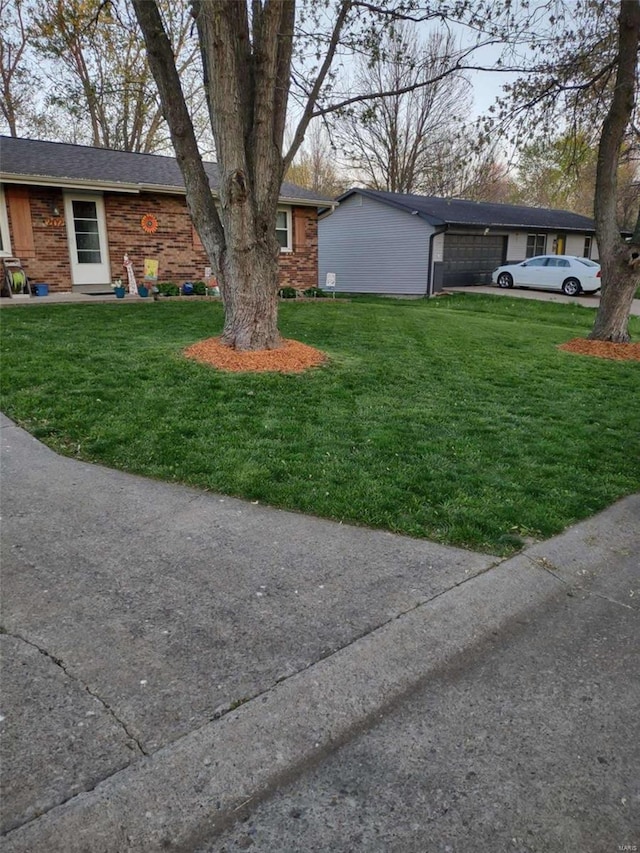 view of front facade with an attached garage, a front lawn, and brick siding