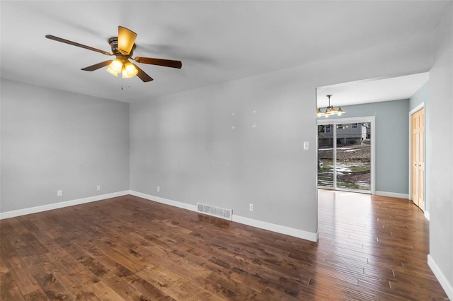 spare room with dark wood-style flooring, visible vents, baseboards, and ceiling fan with notable chandelier