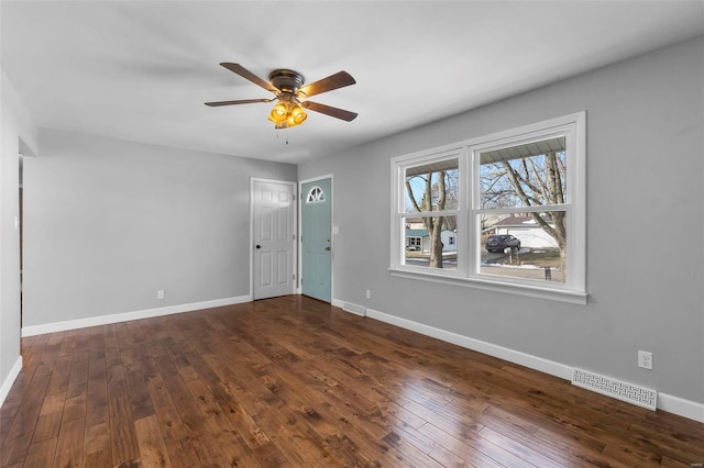 empty room featuring baseboards, visible vents, dark wood finished floors, and a ceiling fan