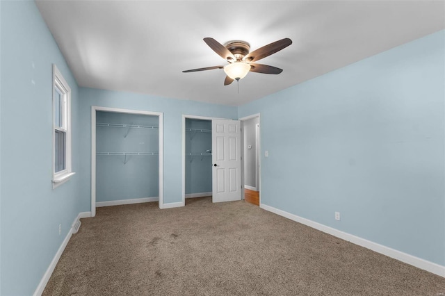 unfurnished bedroom with carpet, ceiling fan, baseboards, and two closets