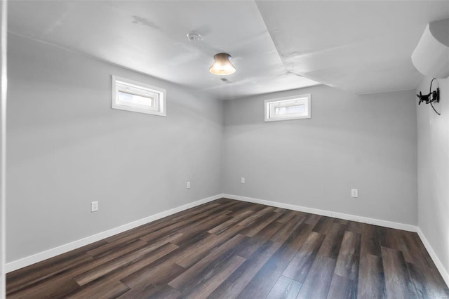 basement with dark wood-style flooring, a healthy amount of sunlight, and baseboards