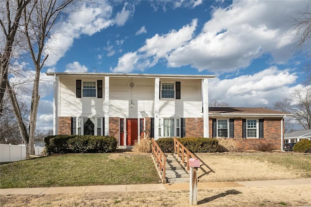 view of front facade featuring brick siding, a front lawn, and fence