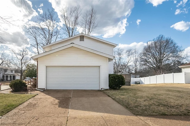 garage with concrete driveway and fence