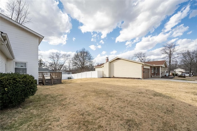 view of yard with a garage, a deck, and fence