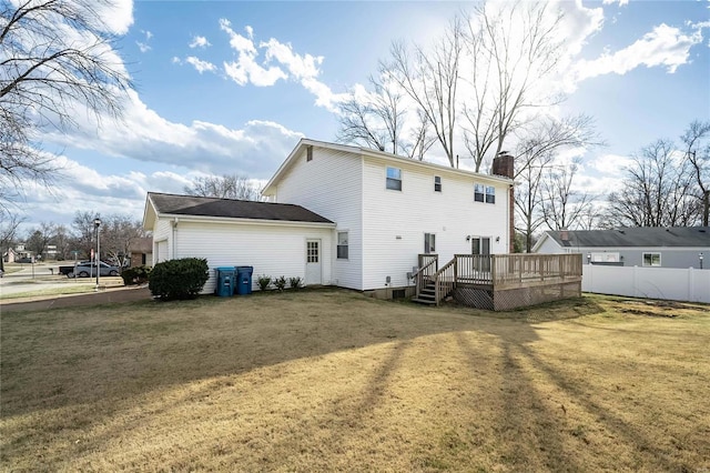 back of house featuring a wooden deck, a lawn, a chimney, and fence