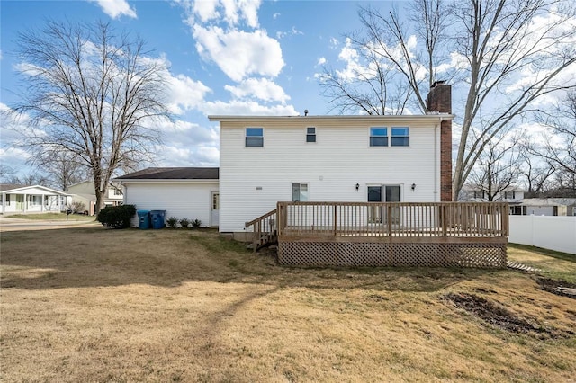 back of property featuring a wooden deck, a lawn, a chimney, and fence