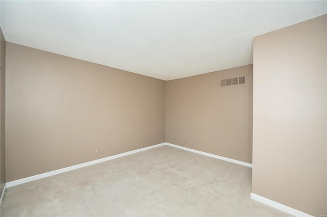 empty room with baseboards, visible vents, and light carpet