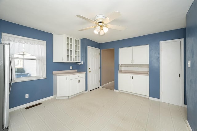 kitchen featuring visible vents, glass insert cabinets, ceiling fan, freestanding refrigerator, and white cabinetry