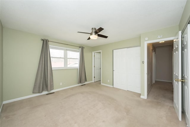 unfurnished bedroom with light carpet, visible vents, a ceiling fan, and baseboards