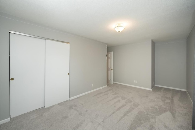 unfurnished bedroom with carpet flooring, baseboards, a closet, and a textured ceiling