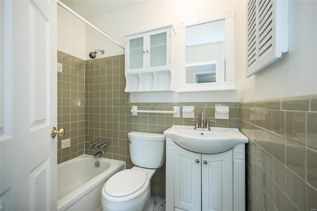 bathroom with toilet, tile walls, shower / washtub combination, and vanity