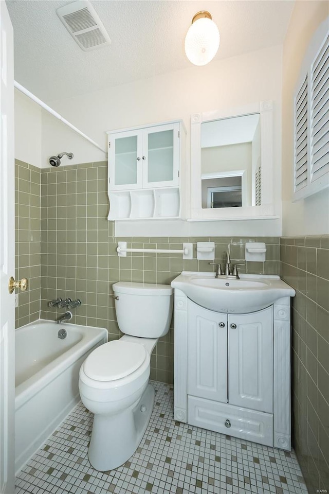 full bathroom featuring vanity, visible vents, tile patterned flooring, tile walls, and toilet