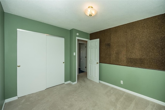 unfurnished bedroom with a closet, a textured ceiling, baseboards, and carpet floors