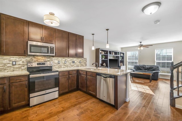 kitchen featuring wood finished floors, backsplash, stainless steel appliances, and a sink