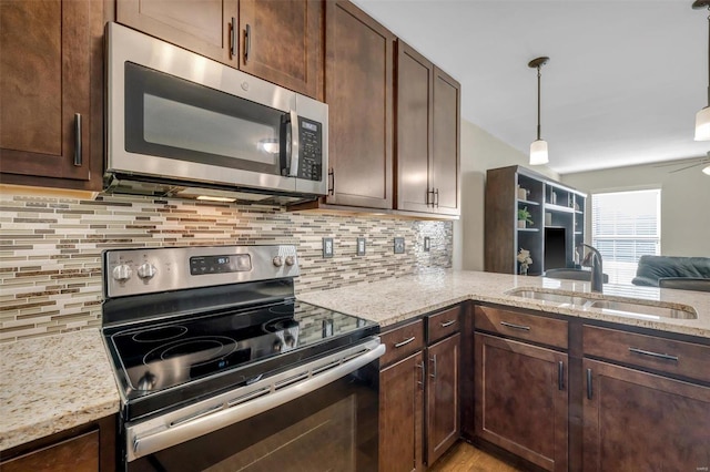 kitchen featuring dark brown cabinetry, light stone counters, appliances with stainless steel finishes, and a sink