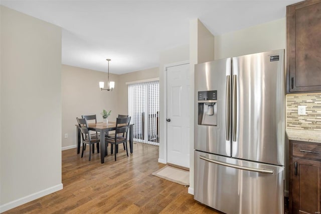 kitchen featuring tasteful backsplash, light wood finished floors, baseboards, dark brown cabinetry, and stainless steel fridge