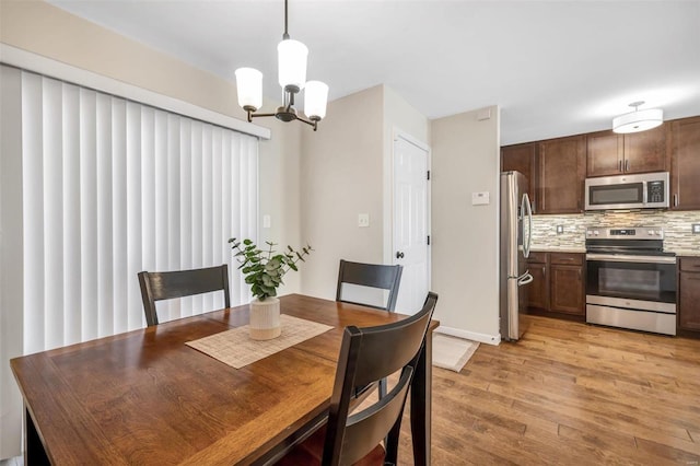 dining area with light wood-type flooring and an inviting chandelier