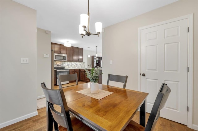 dining room with baseboards, light wood-type flooring, and an inviting chandelier