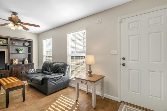 living room featuring light wood-style flooring, baseboards, and ceiling fan