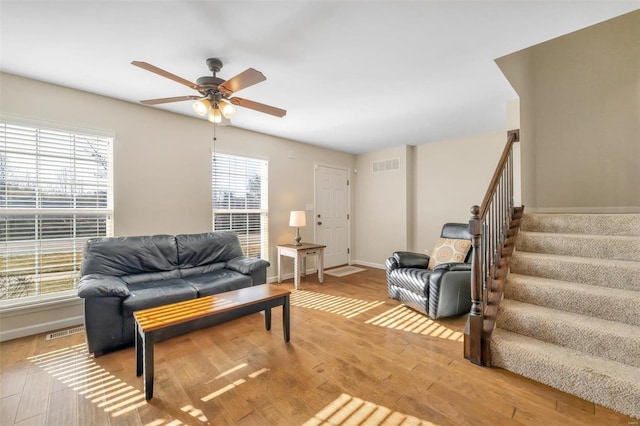 living room featuring stairway, wood finished floors, visible vents, and a healthy amount of sunlight