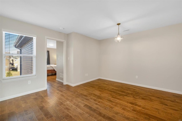 empty room featuring visible vents, baseboards, and hardwood / wood-style flooring