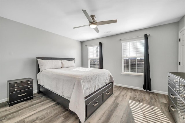 bedroom with visible vents, light wood-style flooring, a ceiling fan, and baseboards