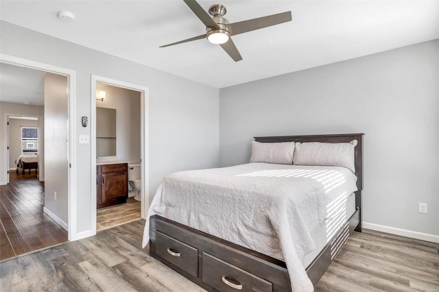 bedroom with ceiling fan, connected bathroom, baseboards, and wood finished floors