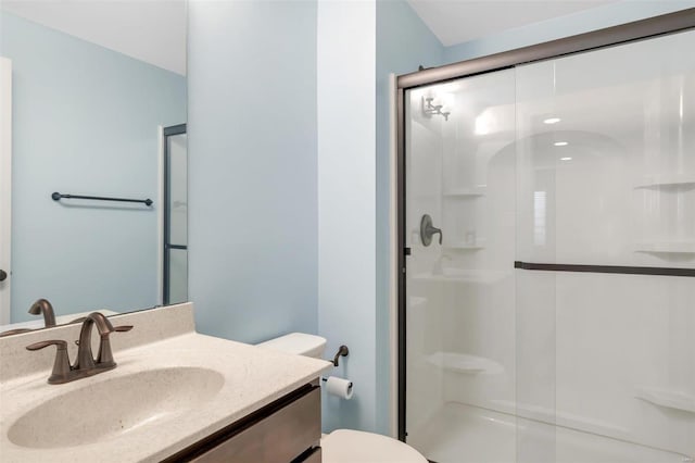 bathroom with a shower stall, toilet, and vanity