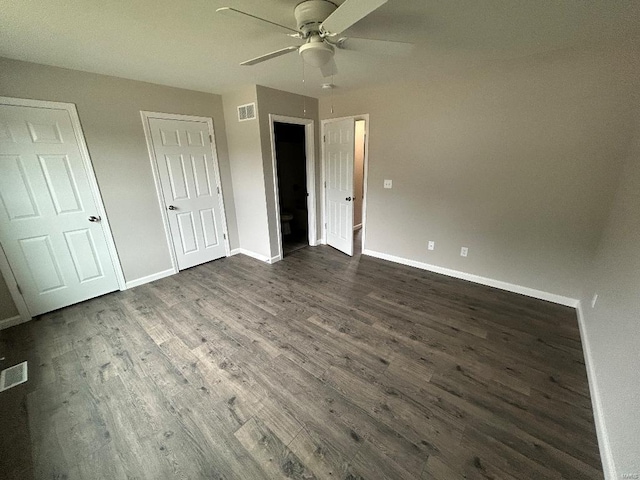 unfurnished bedroom featuring dark wood-type flooring, a ceiling fan, visible vents, and baseboards