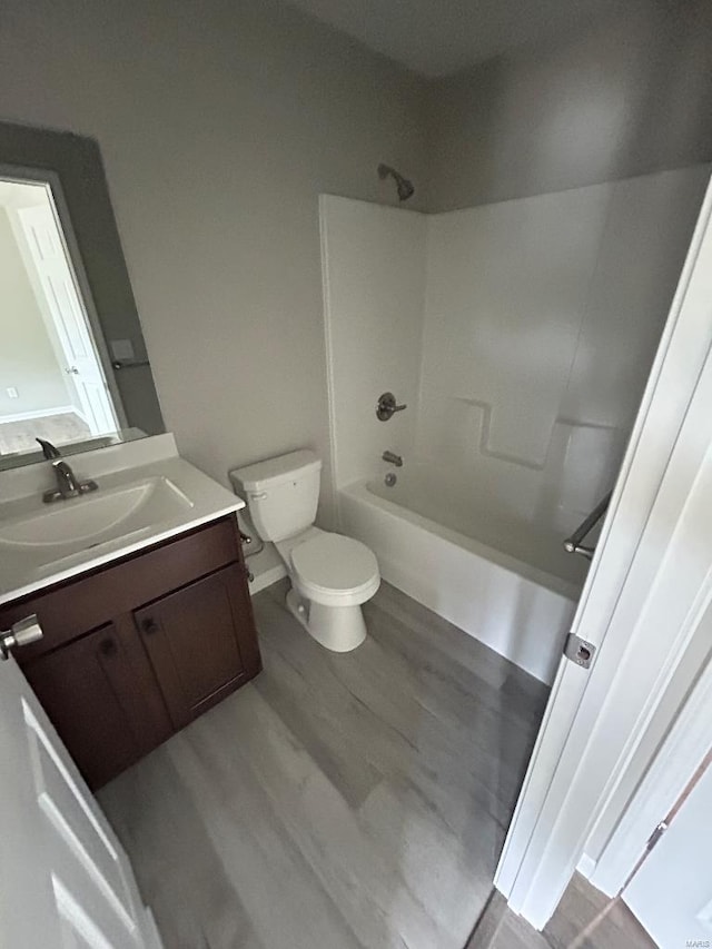 bathroom featuring shower / washtub combination, vanity, toilet, and wood finished floors