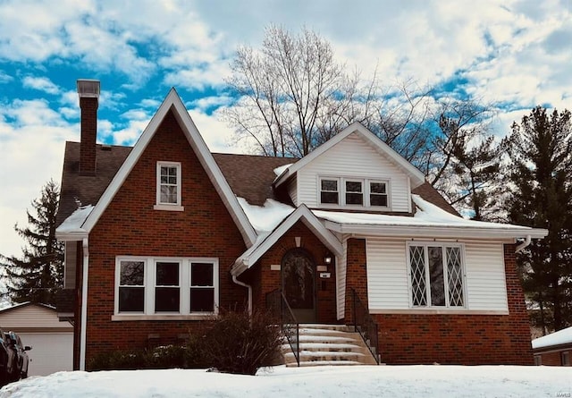 view of front of property with a detached garage, a chimney, an outdoor structure, and brick siding