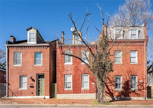 view of front of property with a chimney and brick siding