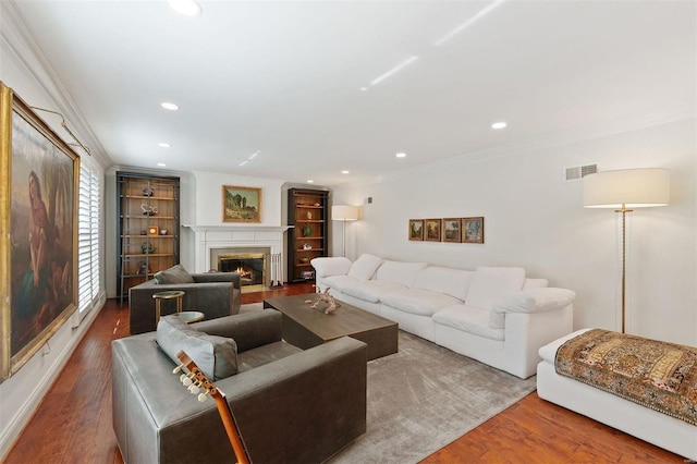 living area with a fireplace with flush hearth, wood finished floors, visible vents, and crown molding