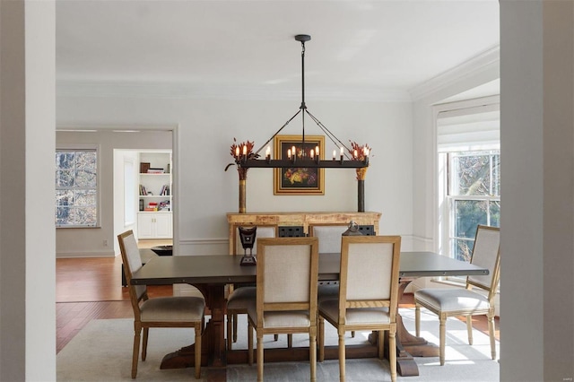 dining space featuring baseboards, ornamental molding, wood finished floors, and a notable chandelier