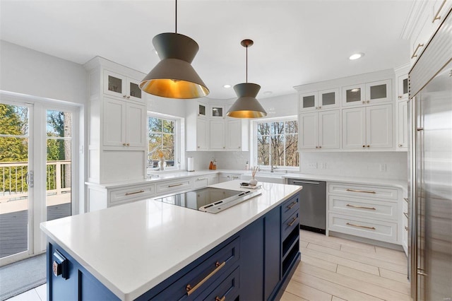 kitchen featuring stainless steel appliances, blue cabinetry, light countertops, and white cabinetry