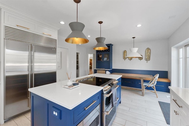 kitchen with white cabinets, blue cabinetry, stainless steel appliances, and light countertops