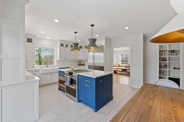 kitchen with stainless steel appliances, wood finish floors, white cabinets, and blue cabinets